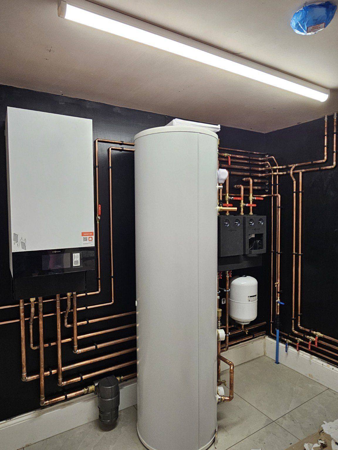Completed plant room installation with neat copper pipework, hot water cylinder and heating components